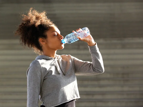 Mulher se hidratando com água.