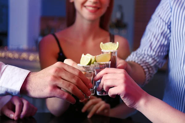 Pessoas brindando um copo de tequila