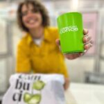 Mulher sorridente segurando um copo sustentável green cups